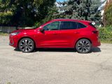 a red car parked in a parking lot with trees in the background