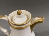 a white and gold coffee pot with a gold lid