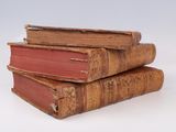 several old books stacked on top of each other on a white surface