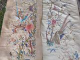 two pieces of cloth with birds and flowers on them sitting on the ground