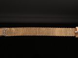 a close up of a gold bracelet on a black background