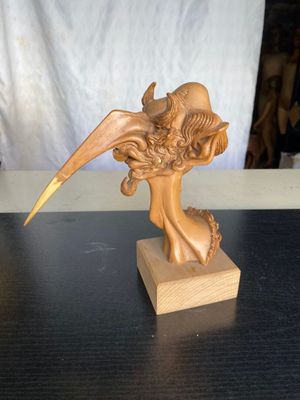 statue représentant une femme avec un oiseau sur la tête, posée sur un socle en bois