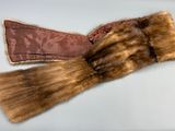 une paire de gants en fourrure marron posés sur une surface blanche