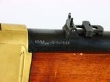 a close up of a rifle on a wooden table with a yellow handle