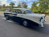 an old black and white car is parked on the side of the road
