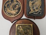 three plaques on a white surface with a wooden plaque in the middle
