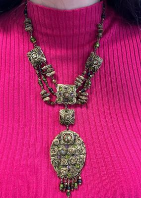 un gros plan sur une femme portant un pull rose et un collier