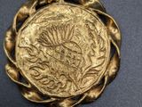 a close up of a gold coin on a black cord
