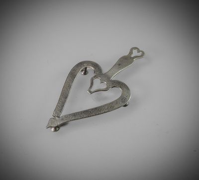 a small metal heart shaped object on a white surface