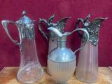 trois vases en argent posés sur une table, sur fond rouge