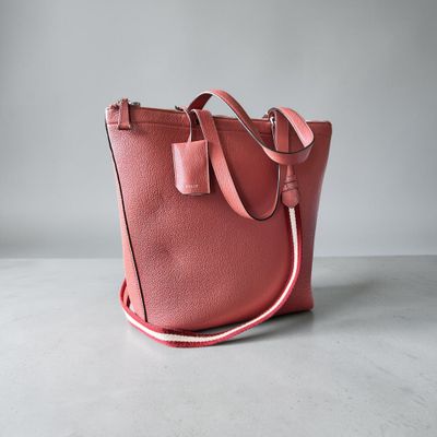 Le sac cabas en cuir rose est posé sur une surface blanche.