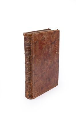 un vieux livre brun posé sur une surface blanche