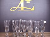 several empty wine glasses lined up on a table with the letter p in the background