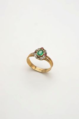 gros plan d'une bague en or avec une pierre verte