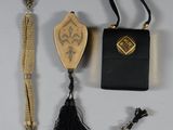 a small black purse with a tassel and other items on a table