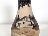 a vase that has a picture of a house on it