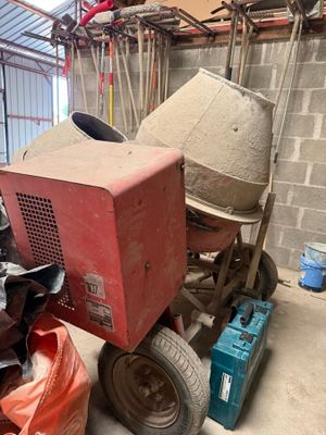 une bétonnière garée dans un garage, à côté d'un tas d'ordures