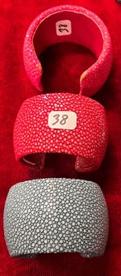 trois bracelets de couleurs différentes posés sur un fond rouge, accompagnés d'une étiquette de prix