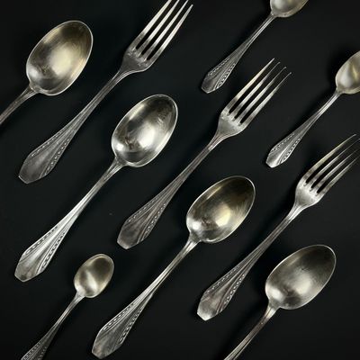 de nombreuses cuillères et fourchettes en argent posées sur un fond noir