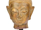 une image représentant une tête de Bouddha dorée posée sur un socle noir