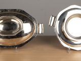 two silver dishes on a wooden table with a gray wall in the background