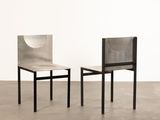 two chairs in a room with concrete floors and a white wall