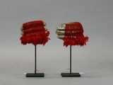pair of red and white hats with feathers on stands on a white surface