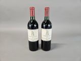 two bottles of red wine sitting next to each other on a table