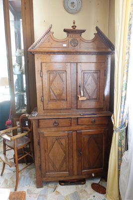 a wooden cabinet in a room with a clock on the wall