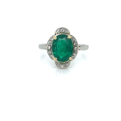 a close up of a ring with a green stone surrounded by diamonds