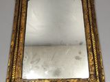 gold framed mirror on a white table with a white wall