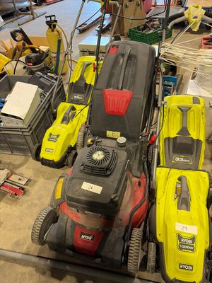 Plusieurs tondeuses à gazon sont alignées sur le sol d'un garage