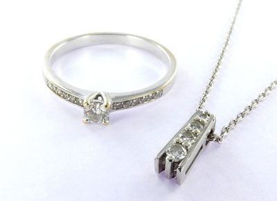 a silver ring and a diamond necklace on a white surface