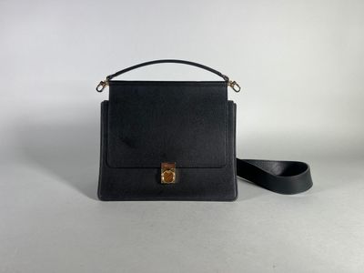 a black leather handbag with a gold clasp on a white background