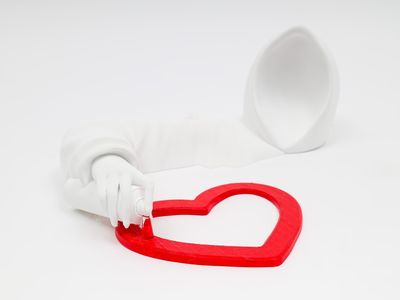 une brosse à dents avec un manche en forme de cœur, à côté d'un tube de dentifrice
