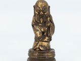 une figurine en bronze représentant un singe assis sur un rocher