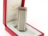 un briquet argenté dans une boîte rouge posée sur une surface blanche