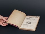 une personne tenant un livre ouvert sur une table, sur fond noir