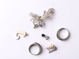 cinq bagues différentes et une broche posées sur un fond blanc