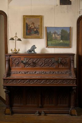 un piano dans un coin d'une pièce où sont accrochés des tableaux