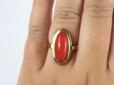 a woman ' s hand holding a ring with a red stone on it