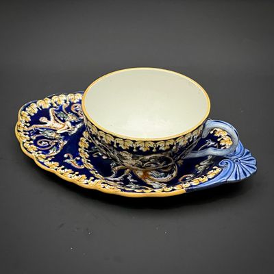 blue and gold coffee cup and saucer on a black background