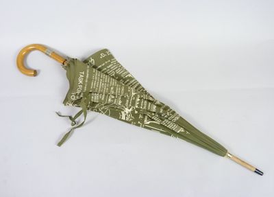 un parapluie vert avec un manche en bois posé sur une surface blanche