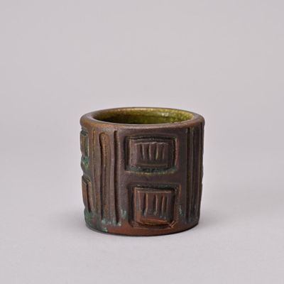 a close up of a brown and green cup on a white surface