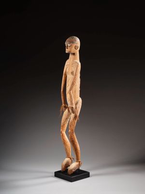 une statue en bois représentant un homme debout sur un socle noir