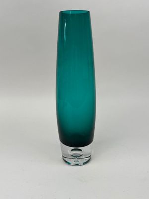 un vase en verre vert posé sur une surface blanche