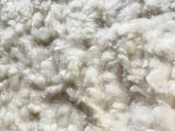 a pile of white wool on a wooden table