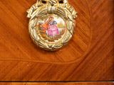 a wooden dresser with a gold knob and a bird on it