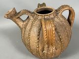 a brown vase with a handle on a white surface