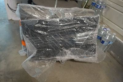 une pile de bouteilles d'eau emballées dans du plastique, posée par terre